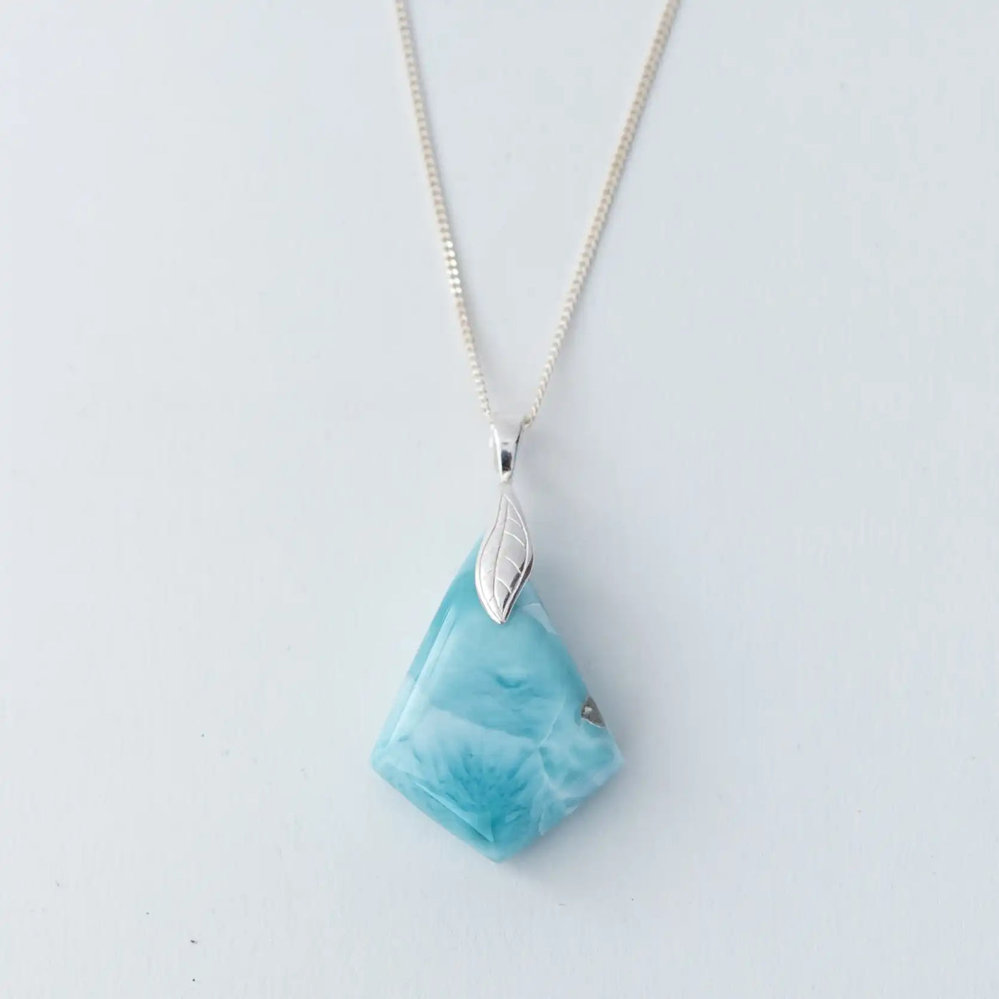 Face recto d'un collier en larimar en forme de losange monté sur une chaîne en argent 925. Pierre naturelle de République Dominicaine de couleur bleu avec différentes teintes de bleu.