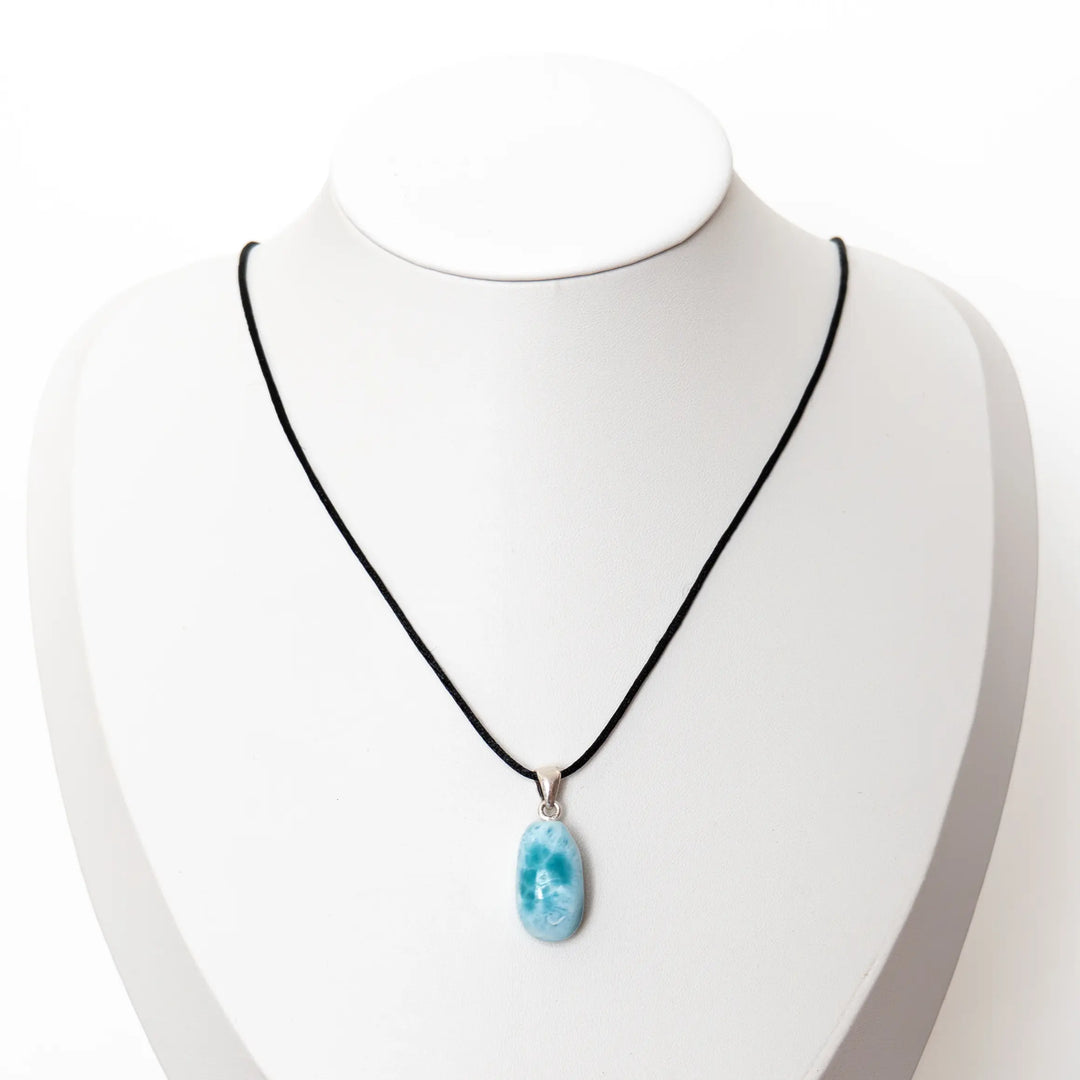 Présentoir en forme de buste sur lequel est monté un collier avec un cordon noir et un pendentif en forme de goutte fait avec la pierre de Larimar. Bijou fait en République Dominicaine.