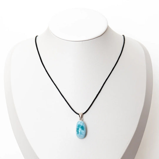 Présentoir en forme de buste sur lequel est monté un collier avec un cordon noir et un pendentif en forme de goutte fait avec la pierre de Larimar. Bijou fait en République Dominicaine.