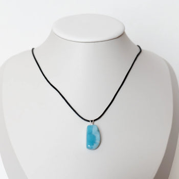 Collier en cordon noir avec un pendentif en pierre de Larimar de République Dominicaine. Bijou posé sur un présentoir en forme de buste.