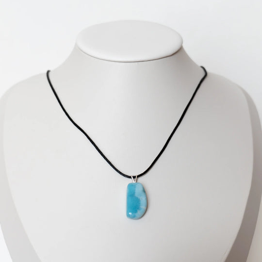 Collier en cordon noir avec un pendentif en pierre de Larimar de République Dominicaine. Bijou posé sur un présentoir en forme de buste.