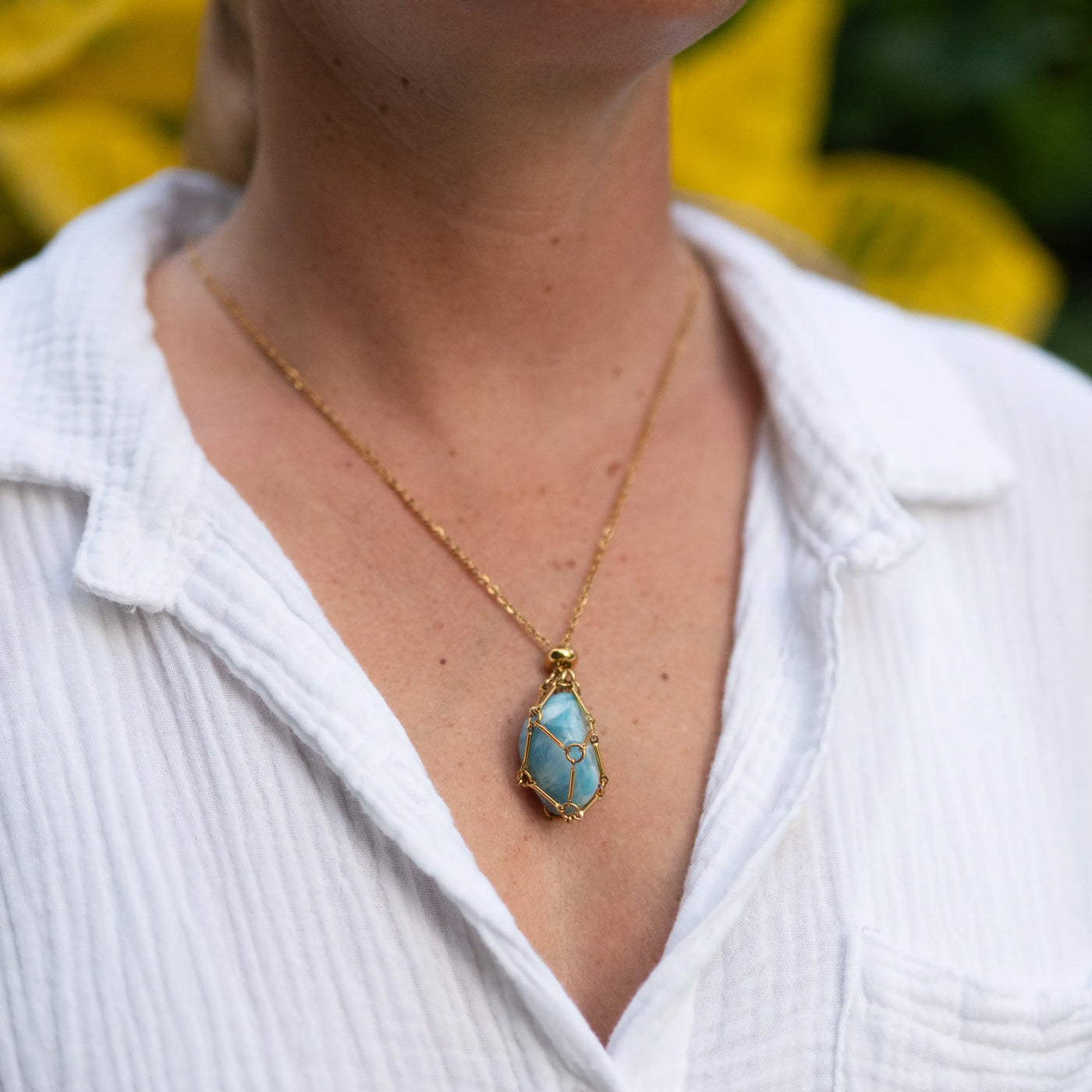 Femme portant un collier cage en acier inoxydable chirurgicale et sa pierre de Larimar de République Dominicaine.