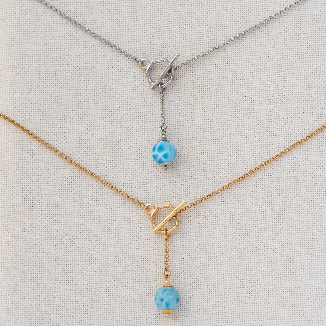 Deux colliers avec des fermoir en T. Une perle de larimar de 11mm de diamètre pend au bout d'une chaine de 2cm. Bijou en acier inoxydable 316L argenté ou doré.