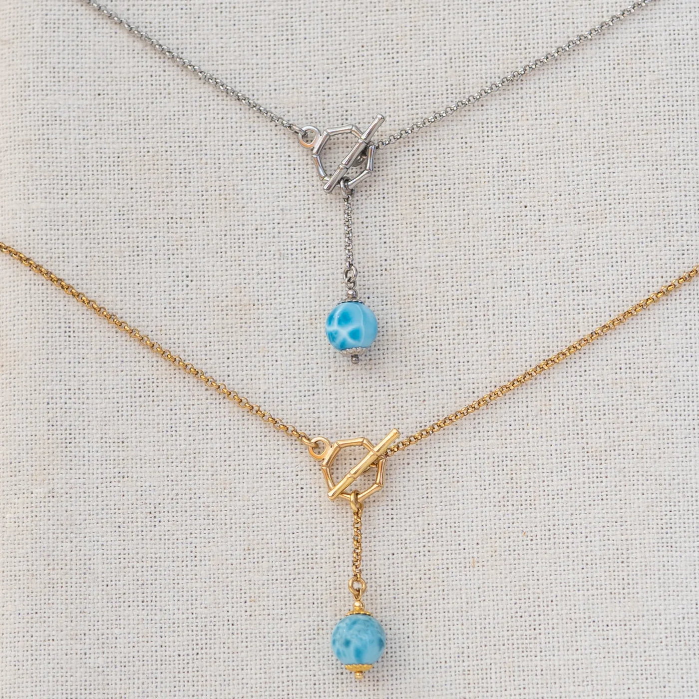 Deux colliers avec des fermoir en T. Une perle de larimar de 11mm de diamètre pend au bout d'une chaine de 2cm. Bijou en acier inoxydable 316L argenté ou doré.