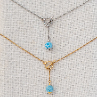 Deux colliers avec des fermoir en T. Une perle de larimar de 11mm de diamètre pend au bout d'une chaine de 2cm. Bijou en acier inoxydable 316L argenté ou doré.