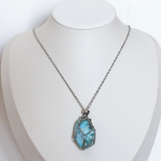 Collier de couleur argenté en acier inoxydable 316L avec une petite cage ouvrable contenant une pierre polie de Larimar.