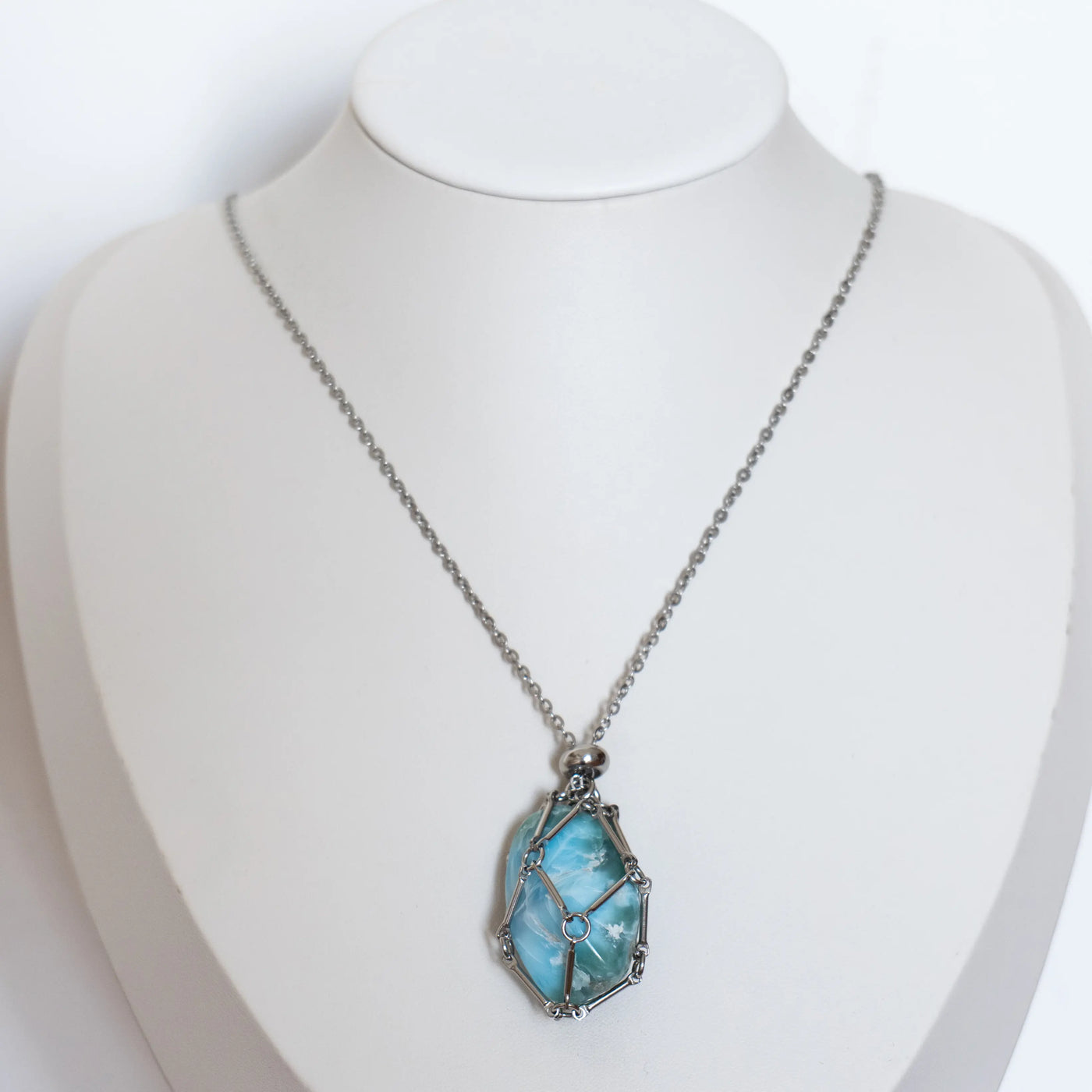 Collier de couleur argenté en acier inoxydable 316L avec une petite cage ouvrable contenant une pierre polie de Larimar.