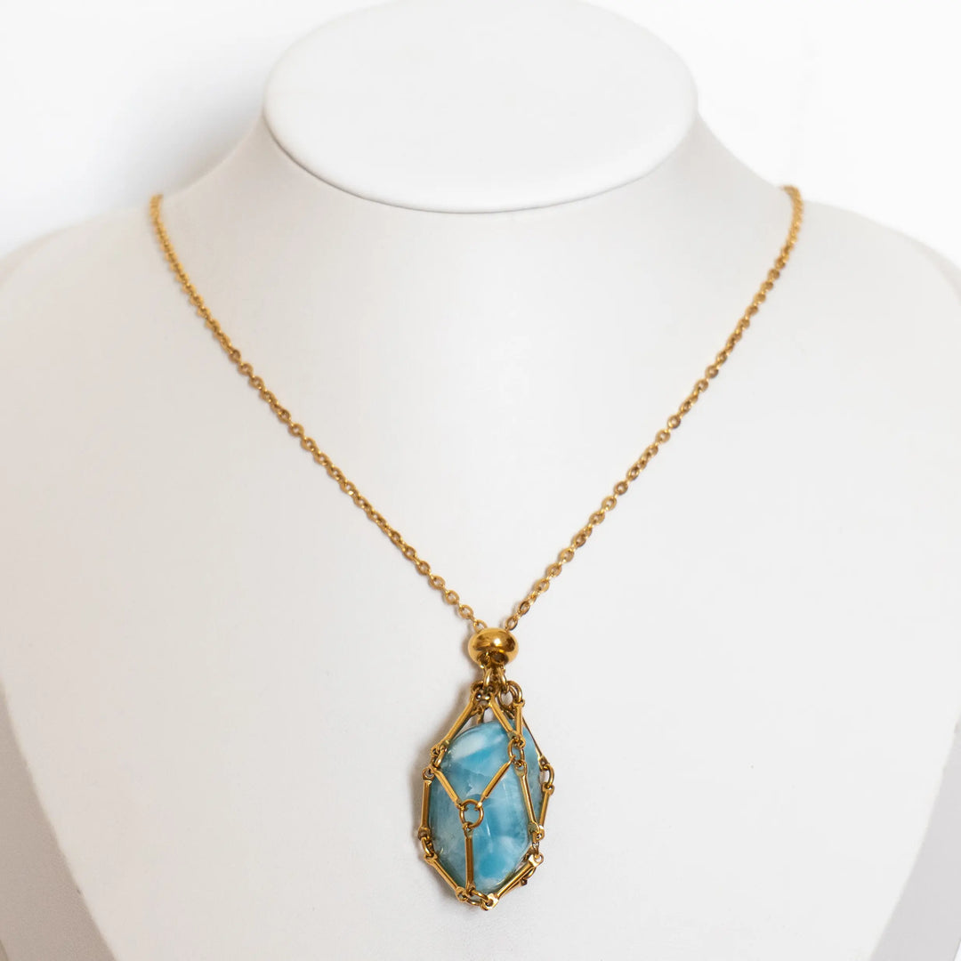 Collier en acier inoxydable doré avec une pierre naturelle de Larimar monté sur un bustier présentoir.