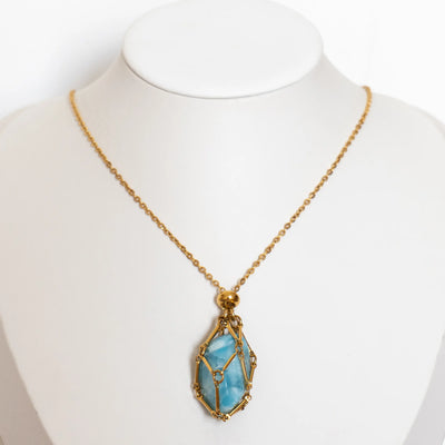 Collier en acier inoxydable doré avec une pierre naturelle de Larimar monté sur un bustier présentoir.