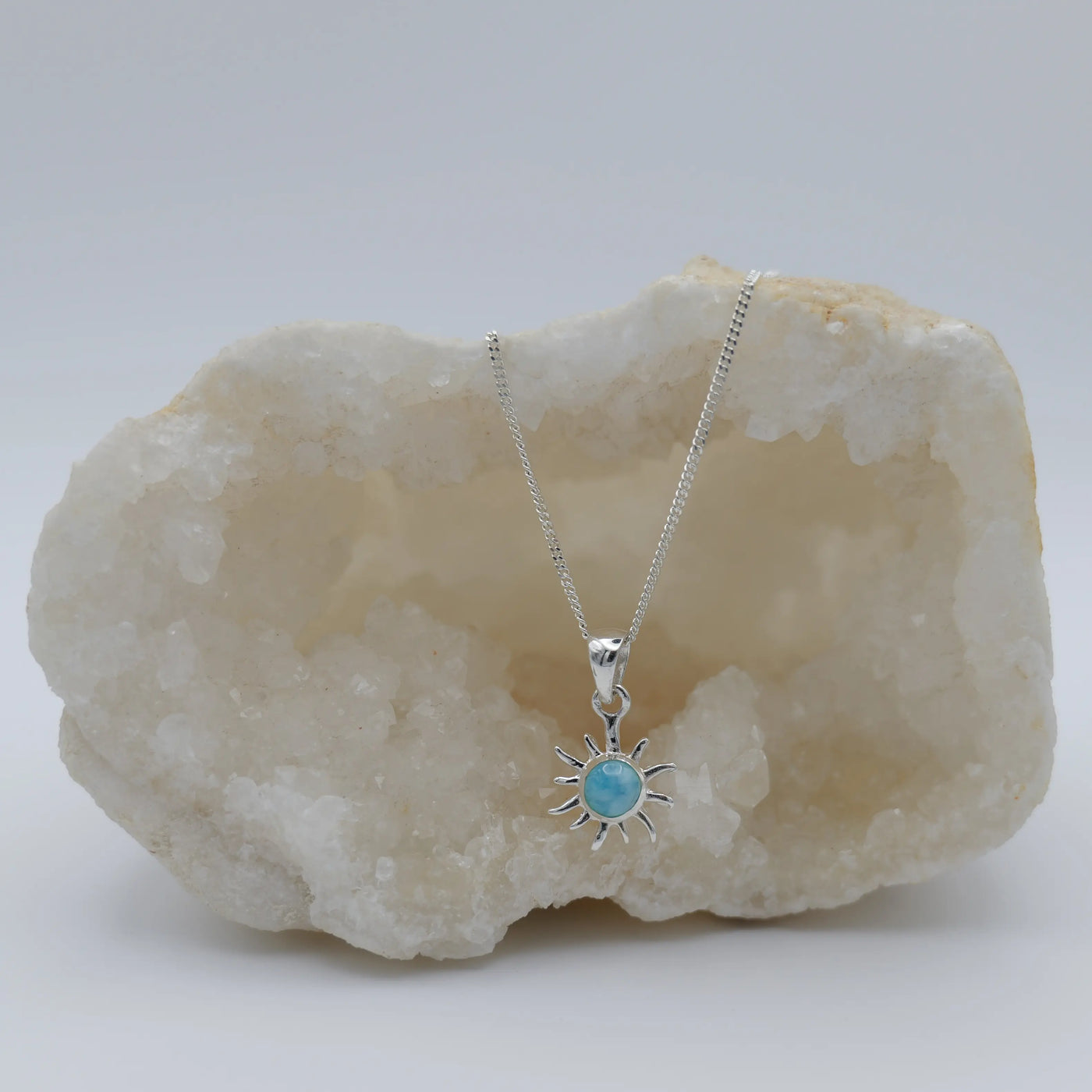 Petit soleil avec une pierre de Larimar ronde en son centre, monté sur une chaîne en argent 925.