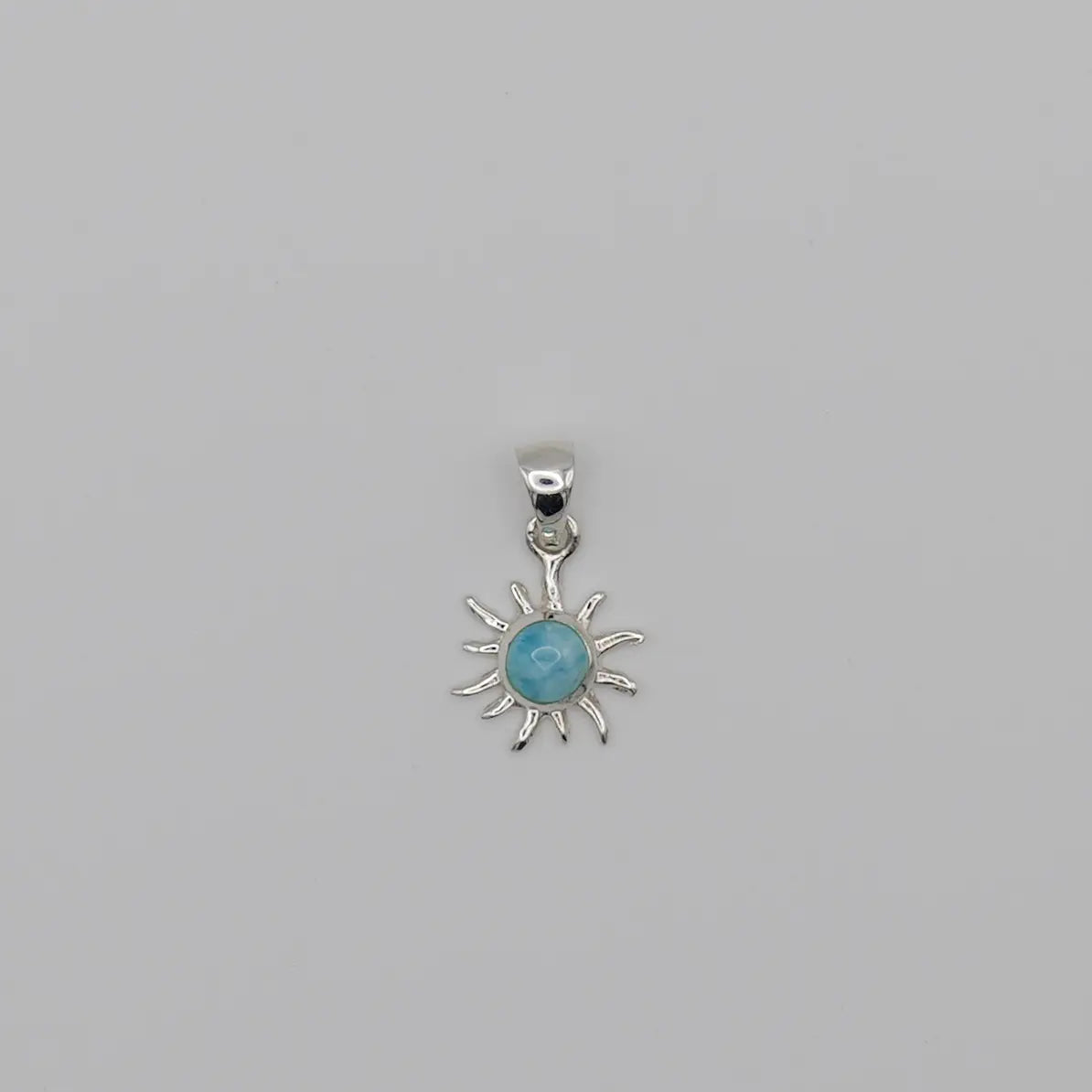Superbe pendentif en forme de soleil. Bijou fait à la main avec une pierre naturelle bleue, du Larimar, sertie au centre du soleil.