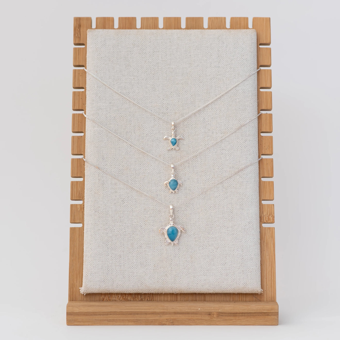 Présentoir avec trois colliers en argent 925 et leur tortue en argent  925 et larimar. Chaque tortue est de taille différente. Larimar origine République Dominicaine.
