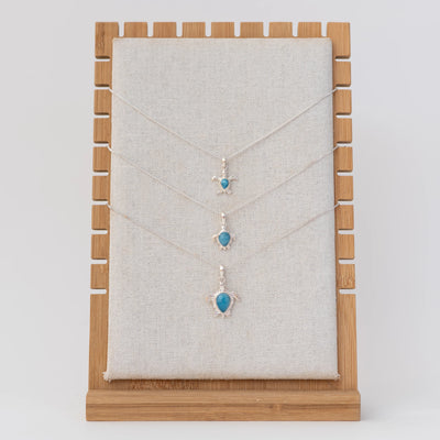 Présentoir avec trois colliers en argent 925 et leur tortue en argent  925 et larimar. Chaque tortue est de taille différente. Larimar origine République Dominicaine.