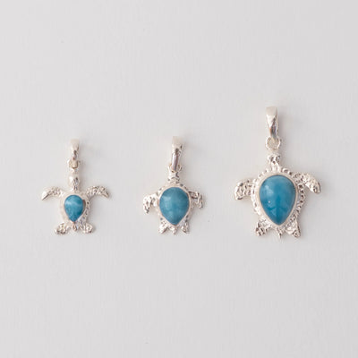Trois bijoux en forme de tortues, faite en argent 925, avec sur chacune une pierre de larimar de République Dominicaine de couleur bleue. La pierr de larimar sur chaque tortue à une forme de goutte inversée.