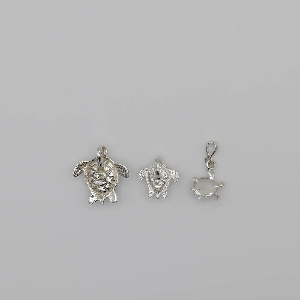 Pendentifs tortues au nombre de 3 vue de verso, chacun fait en argent 925, travaillés artisanalement.