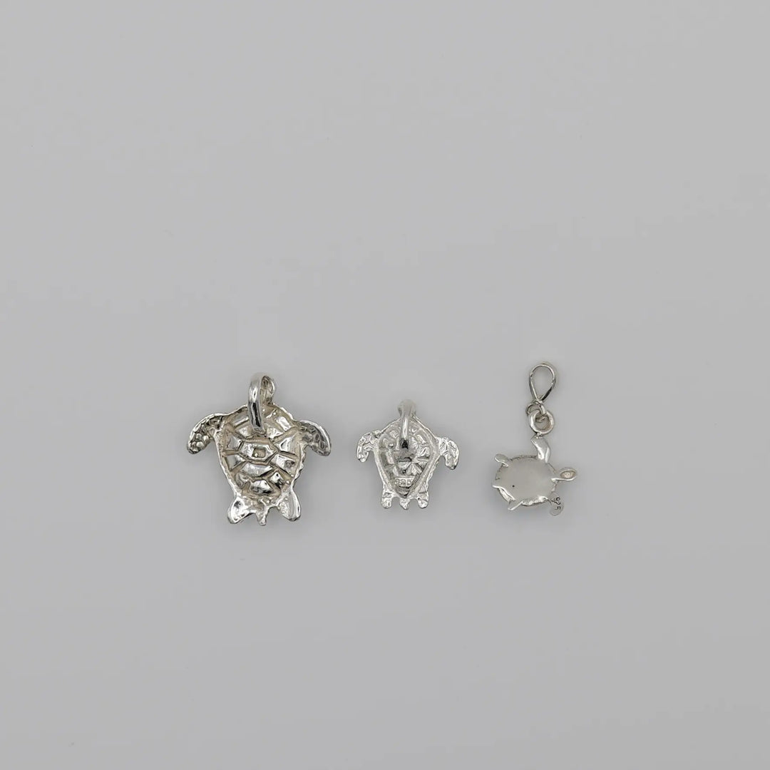 Pendentifs tortues au nombre de 3 vue de verso, chacun fait en argent 925, travaillés artisanalement.