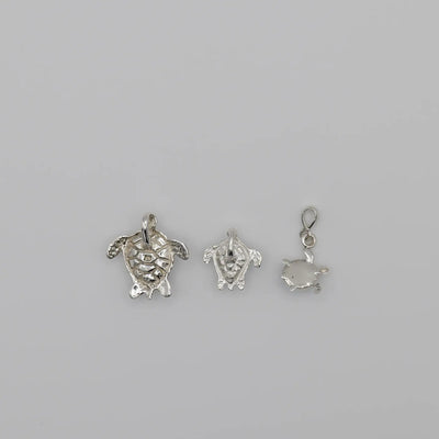 Pendentifs tortues au nombre de 3 vue de verso, chacun fait en argent 925, travaillés artisanalement.