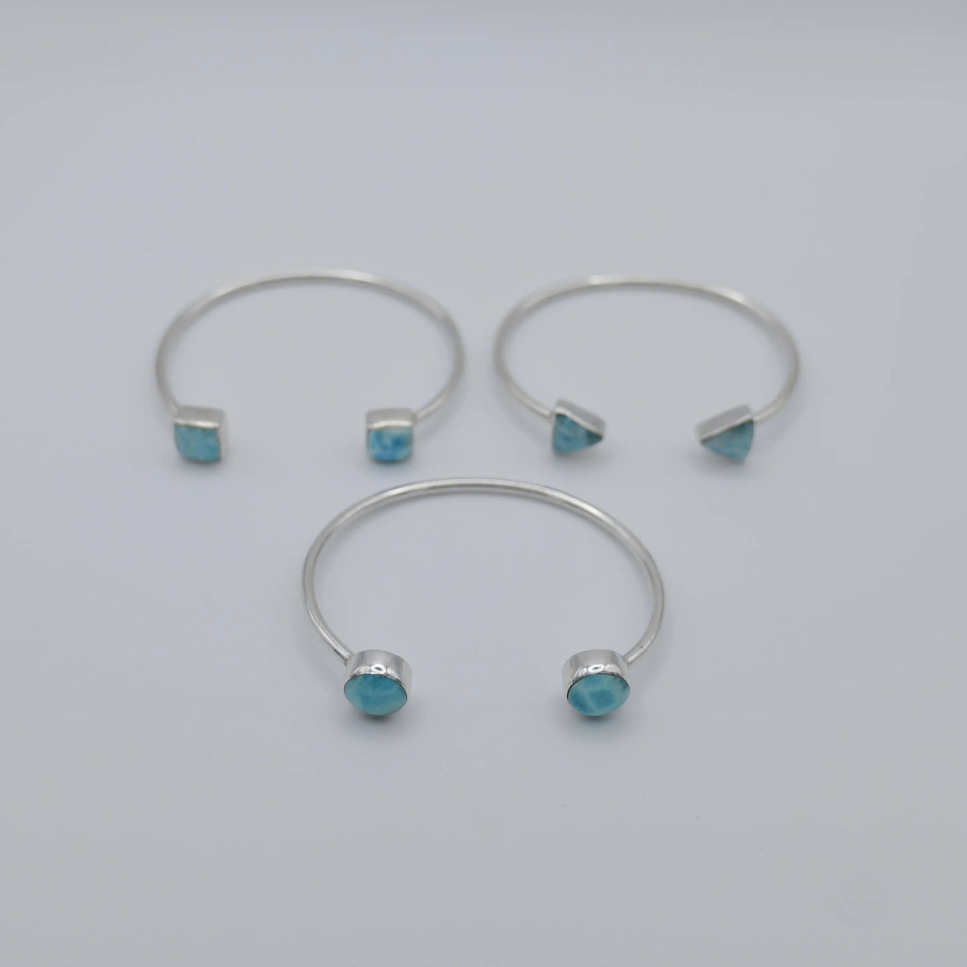 Trois joncs en argent 925 avec du Larimar de couleur bleu de différentes formes sur chaque extrémités des joncs.