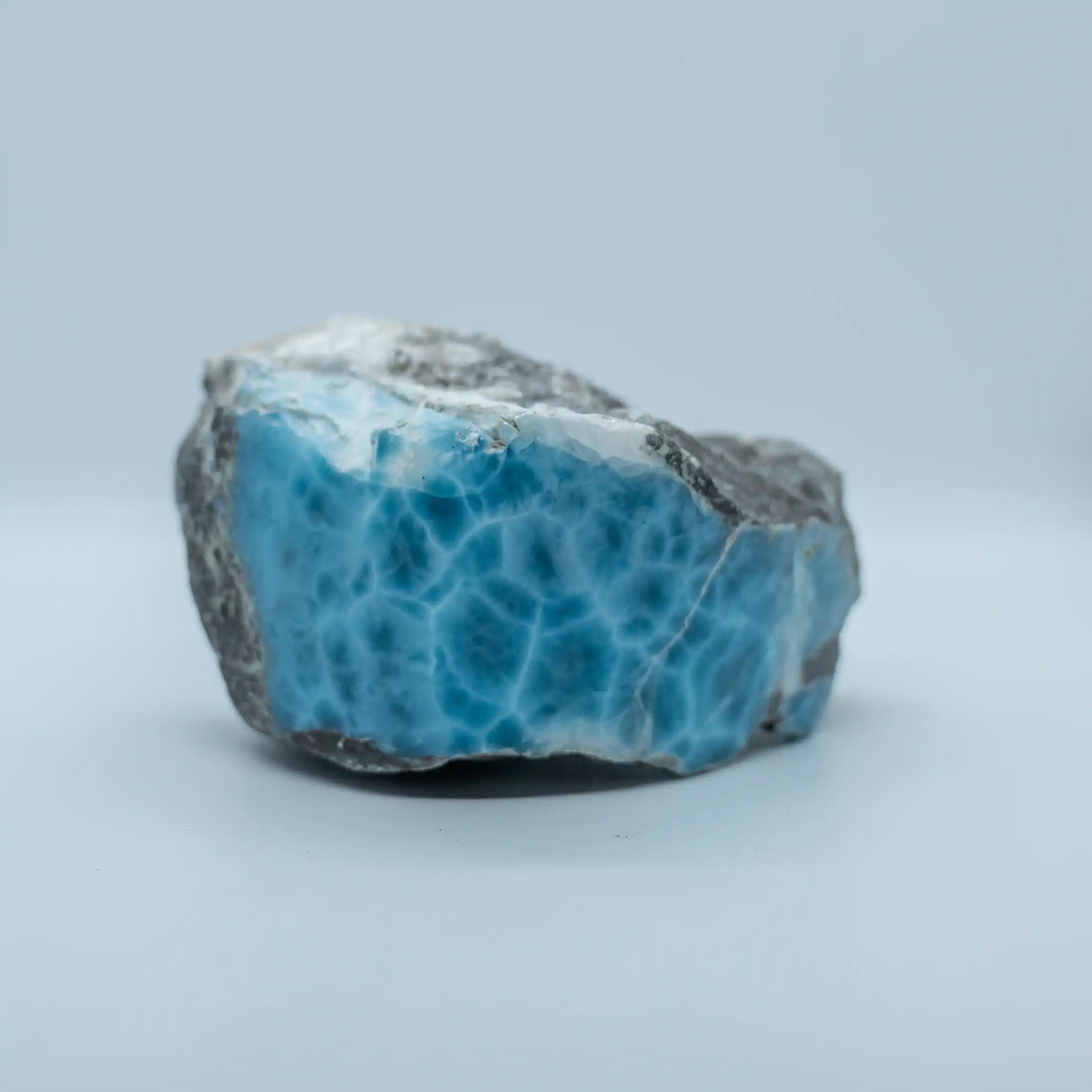 Bloc de pierre naturelle de Larimar vue de face, sur fond blanc. La qualité du larimar est exceptionnelle de part sa couleur bleue intense et la présence d'un maillage blanc rare. Pierre pour collectionneur.