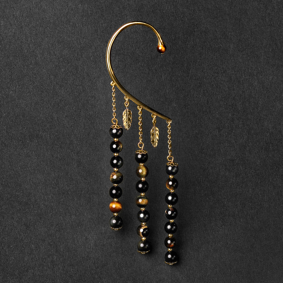 Orparima Tour d'oreille modèle "Protection" de la Collection Energies, sur fond noir. Bijou doré à l'or fin 24 Carats; Perles créées à partir de pierres naturelles.