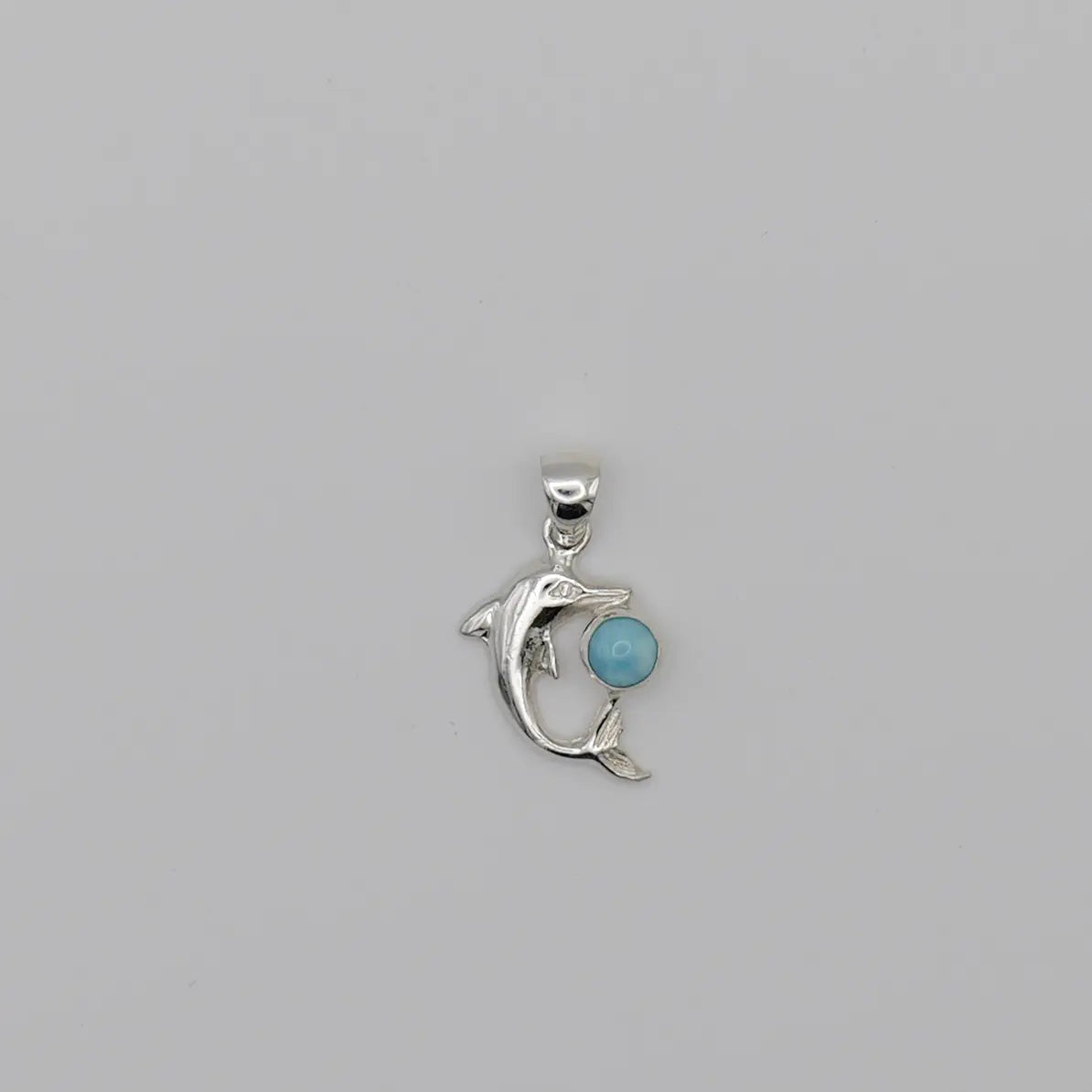 Dauphin en argent 925 avec sa bélière, pouvant être monté sur une chaîne pour faire un collier. Pierre naturelle de Larimar de couleur bleu entre le museau et la queue du dauphin.