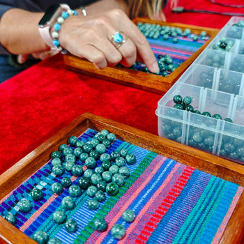 Plusieurs dizaines de perles de pierre naturelle de Jade jaguar du Guatemala réparties dans des plateaux en bois marron foncé. Perles de couleur verte moucheté d'un vert plus pale. 