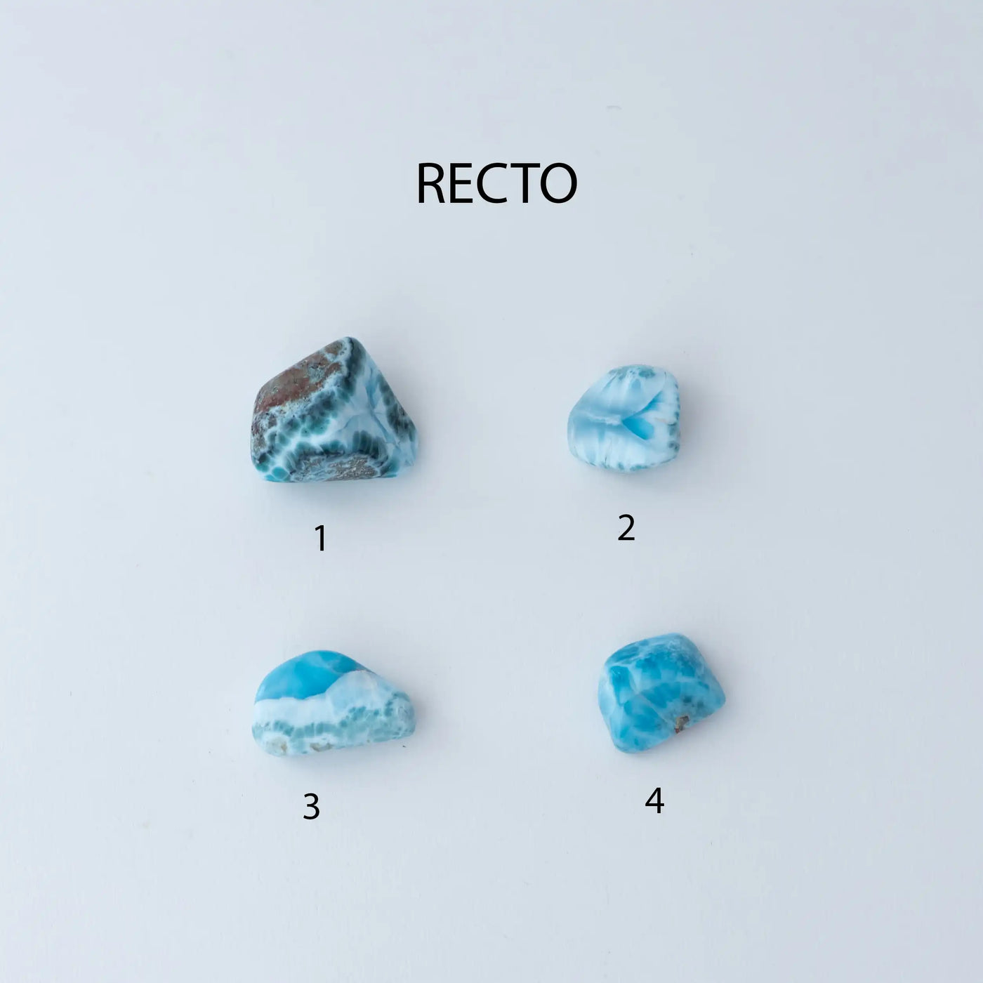 Photo de quatre pierres roulées faite en Larimar, une pierre d'énergie de République Dominicaine. Chaque pierre est différente, avec différentes couleur de bleu, de blanc et de vert. La pierre numéro une et la numéro quatre ont des incrustations de roche de couleur marron.