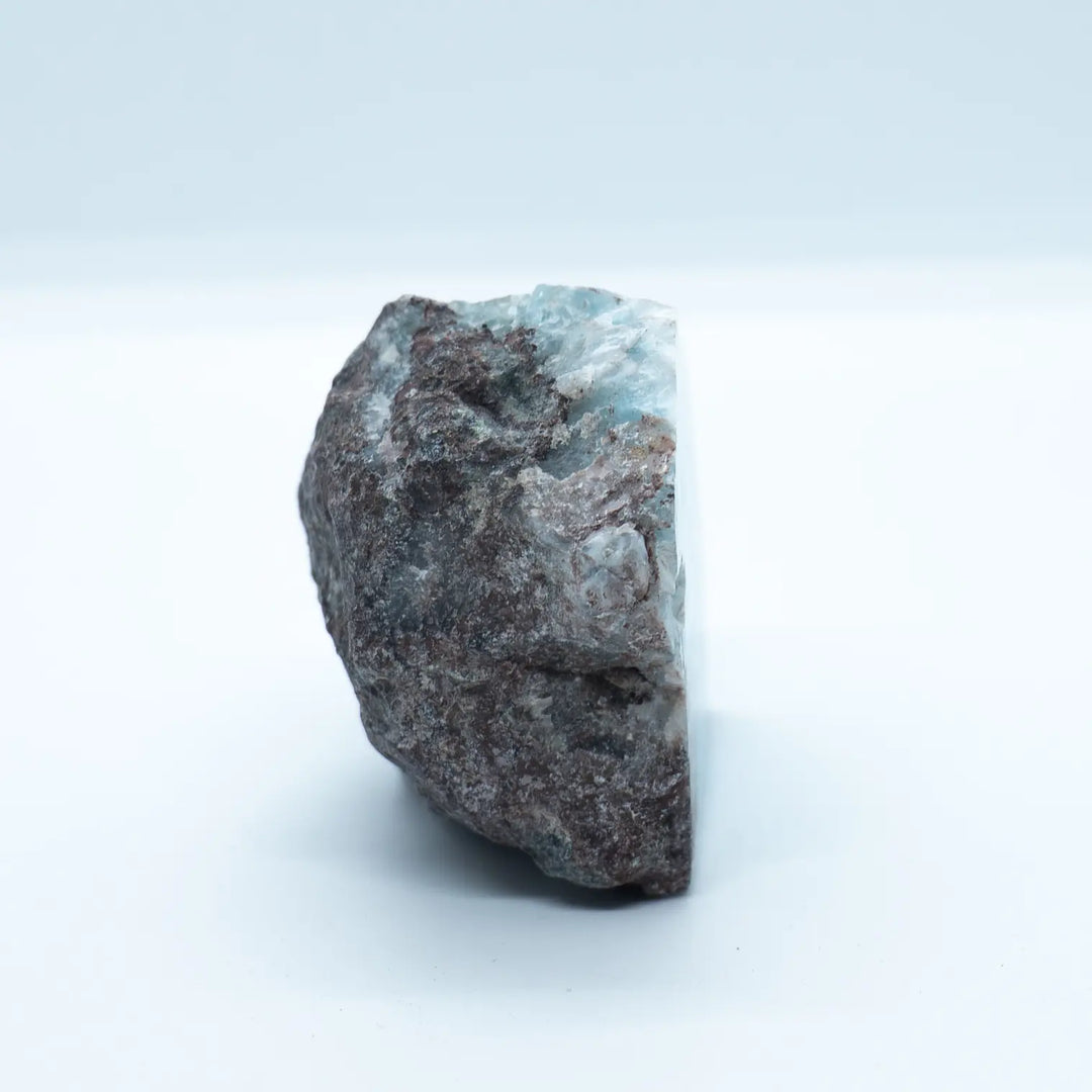 Pierre naturelle de Larimar vue de profil. La majeur partie de cette pierre est de la roche naturelle, avec la présence notable de Larimar de couleur bleue sur le haut du bloc.