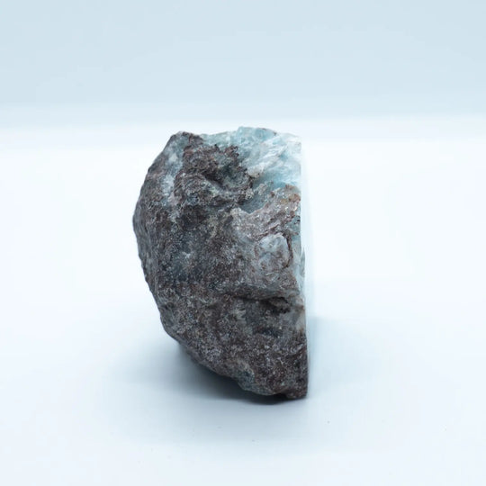 Pierre naturelle de Larimar vue de profil. La majeur partie de cette pierre est de la roche naturelle, avec la présence notable de Larimar de couleur bleue sur le haut du bloc.