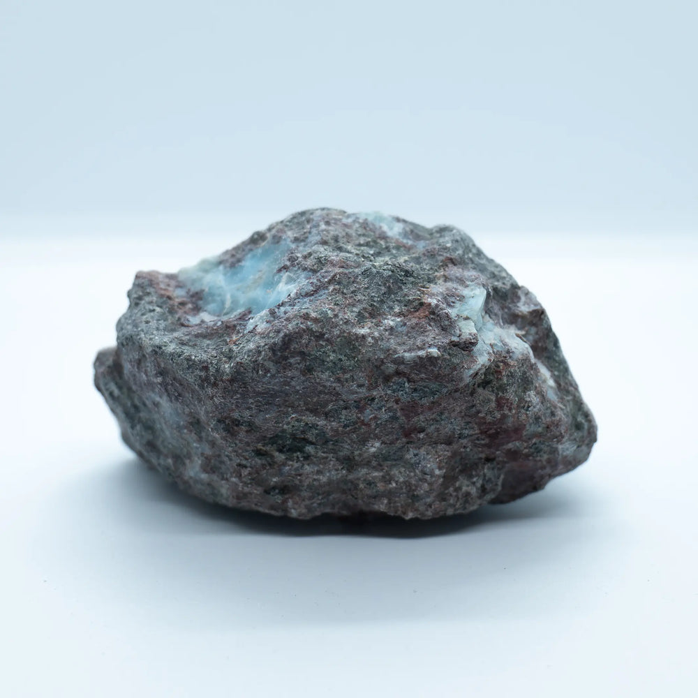 Bloc de roche vue de dos sur fond blanc, on note la présence de Larimar sur la partie gauche caractéristique par sa couleur bleue. Cette pierre naturelle est extraite en République Dominicaine dans une mine situé à Barahona dans le sud du pays.