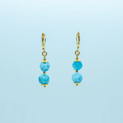 Boucles d'oreilles en acier inoxydable 316L doré sur fond blanc. Chaque boucle d'oreille à deux perles de larimar pendantes.