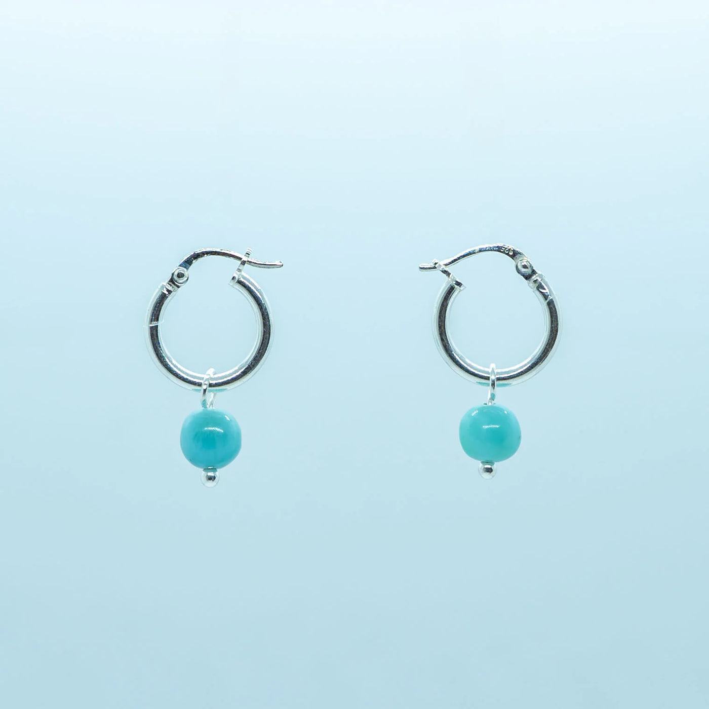 Photo d'une paire de boucles d'oreilles en argent 925, en formme de petite créoles, avec une pierre de Larimar pendante
