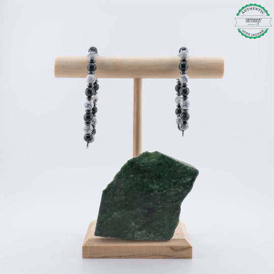 Deux bracelets de tailles différentes présentés sur un présentoir en bois sur lequel est posé une pierre naturelle brute de Jade Jaguar Maya d&