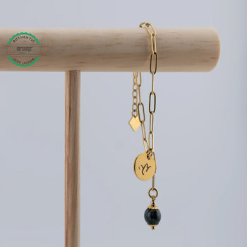 Bracelet en acier inoxydable doré suspendu à un présentoir en bois. Bijou fait artisanalement en République Dominicaine avec une perle de Jade Jaguar vert foncée venant du Guatemala.