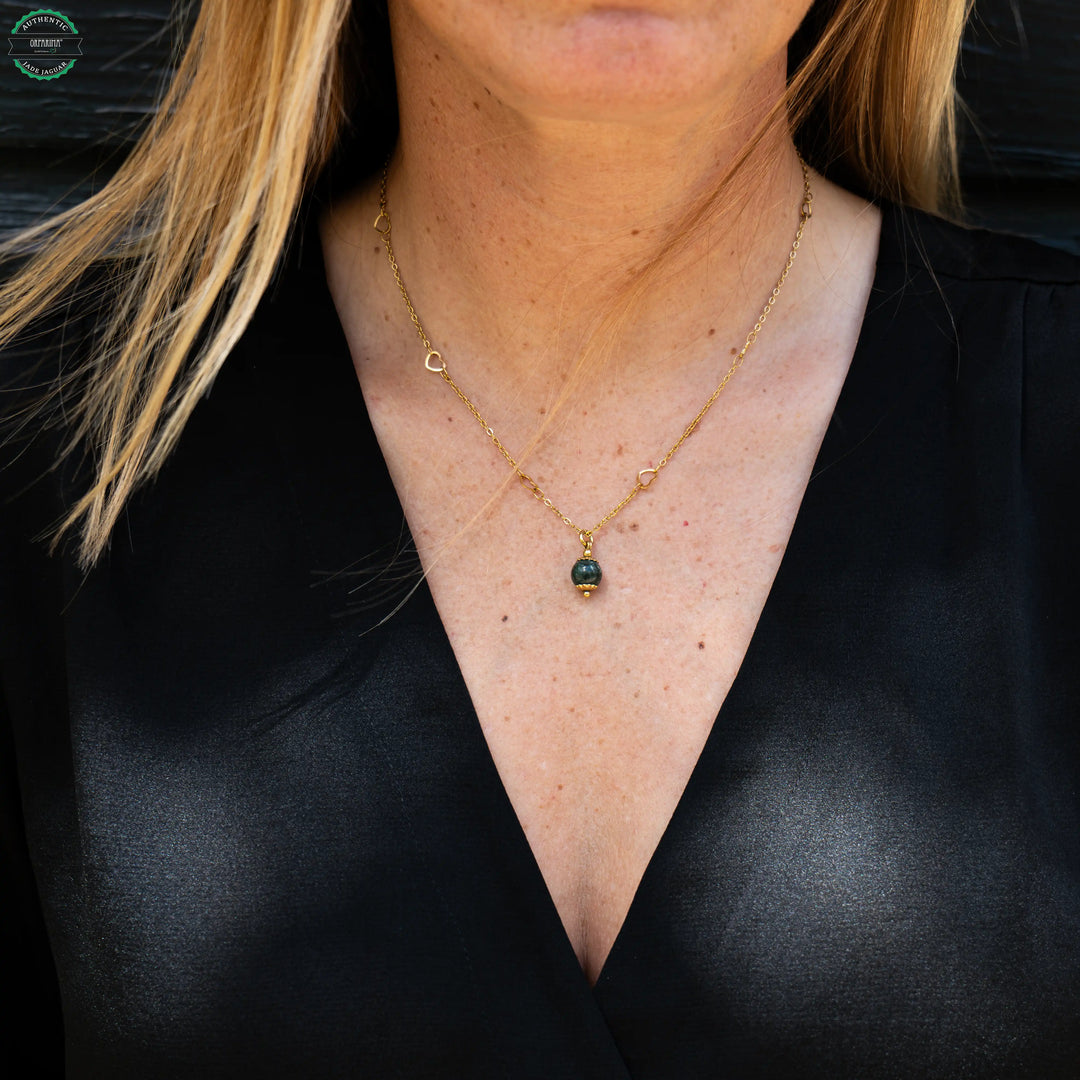Collier avec une maille contenant de petits cœur faite en acier inoxydable chirurgical sur lequel est monté une perle de Jade Jaguar vert foncé du Guatemala.