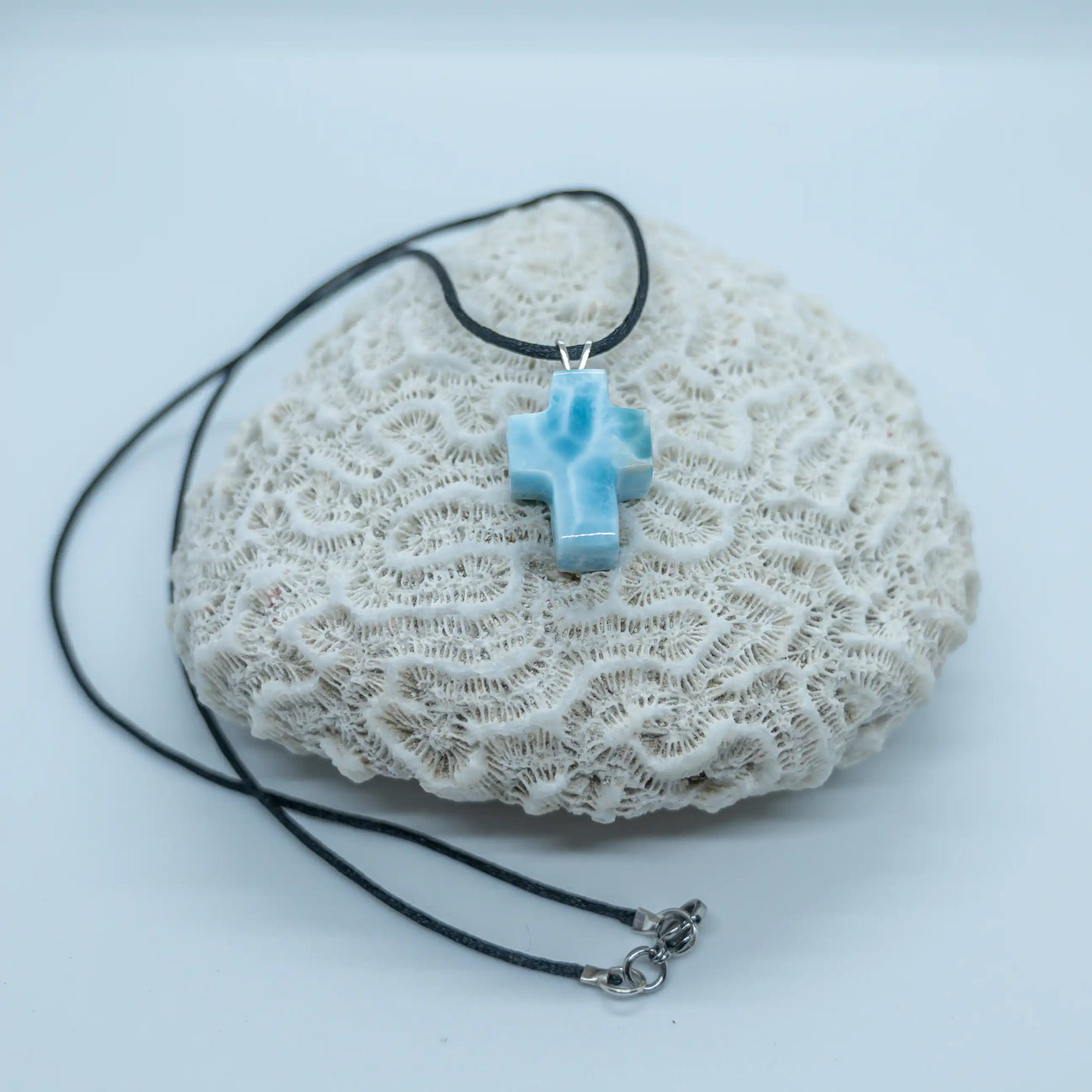 Collier avec une croix en Larimar bleu montée sur un fil noir et ses attaches en acier inoxydable 316L. Le Larimar vient de République Dominicaine possède plusieurs nuances de bleu.