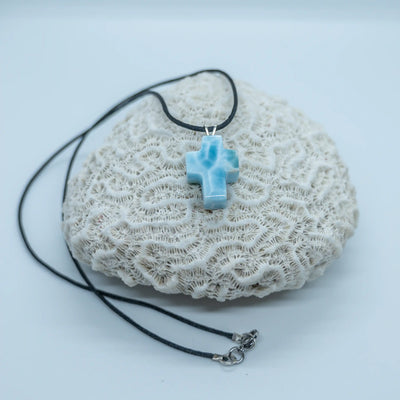 Collier avec une croix en Larimar bleu montée sur un fil noir et ses attaches en acier inoxydable 316L. Le Larimar vient de République Dominicaine possède plusieurs nuances de bleu.