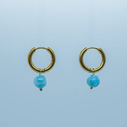 Paire de créoles dorées montées avec une perle de Larimar de couleur bleu. Bijoux en acier inoxydable 316L avec un plaquage PVD doré.