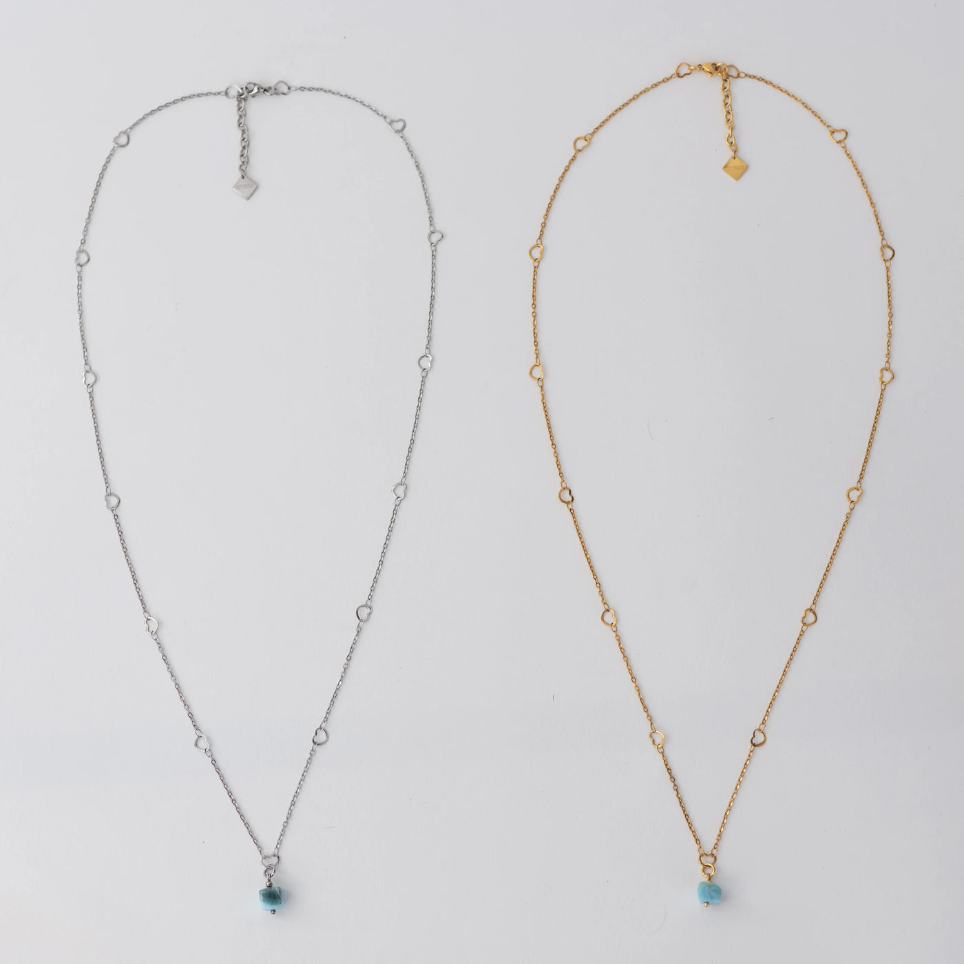 Deux sautoirs sont posés sur fond blanc. Ces sautoirs ont un pendentif en Larimar et sont fait en acier inoxydable chirurgical, en version argenté et en version doré. Chaque collier à une chaîne d’extension avec une breloque orparima.