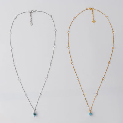 Deux sautoirs sont posés sur fond blanc. Ces sautoirs ont un pendentif en Larimar et sont fait en acier inoxydable chirurgical, en version argenté et en version doré. Chaque collier à une chaîne d’extension avec une breloque orparima.