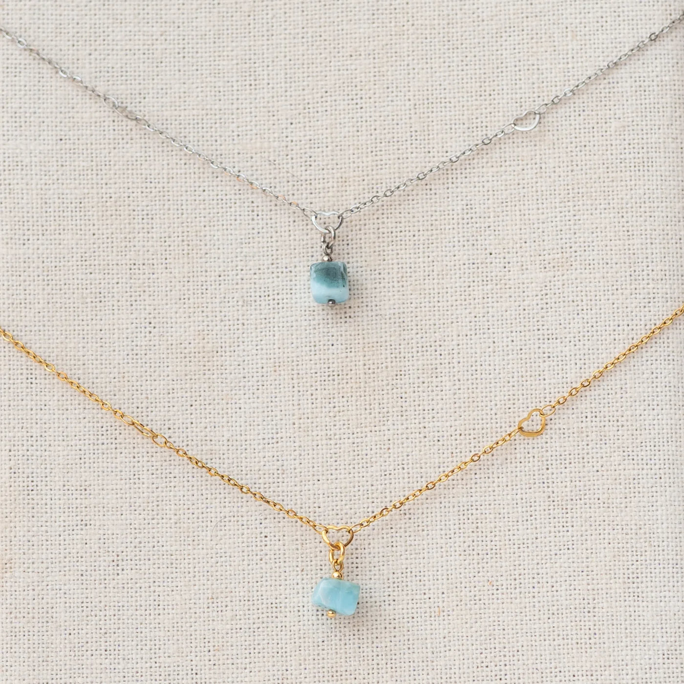 photo macro de deux sautoirs en acier inoxydable chirurgicale avec leur pendentif en pierre naturelle de Larimar. Bijou fait à la main unique au monde.