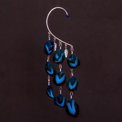 Tour d'oreille faisan electrik de couleur bleue, bijou qui se pose sur l'oreille droite, bijou original et chic. Bijou seul sur fond noir, trois pendants ornés de plume bleues et deux petits après en forme de plume doréau palladium.