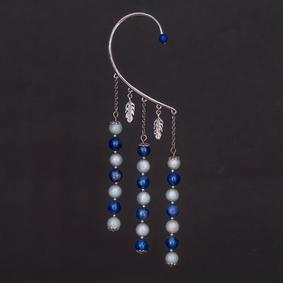 Tour d'oreille de couleur argenté avec ses deux breloque en forme de feuille, ses trois pendants avec des perles bleu de deux teintes différentes. Une perle d'énergie termine le tour d'oreille sur le haut.