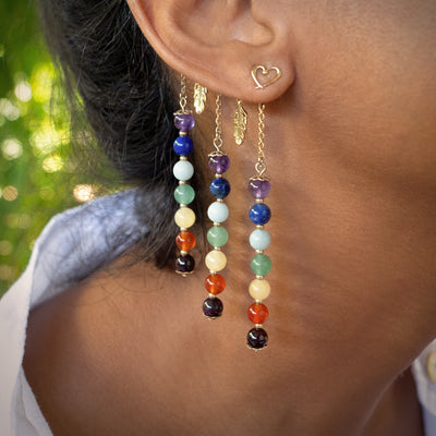 Les boucles d'oreilles "Coeur" portées par Maritza, dorées dans un bain d'or 24 Carats, habillent le Tour d'oreille Orparima "7 Chakras".