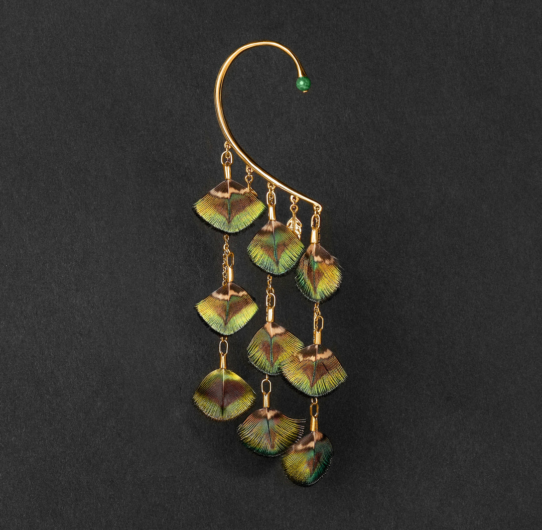 Orparima Tour d'oreille modèle "Le Paon" de la Collection Plumes, sur fond noir. Ce tour d'oreille est orné d'une Jade d'Afrique sur le devant.