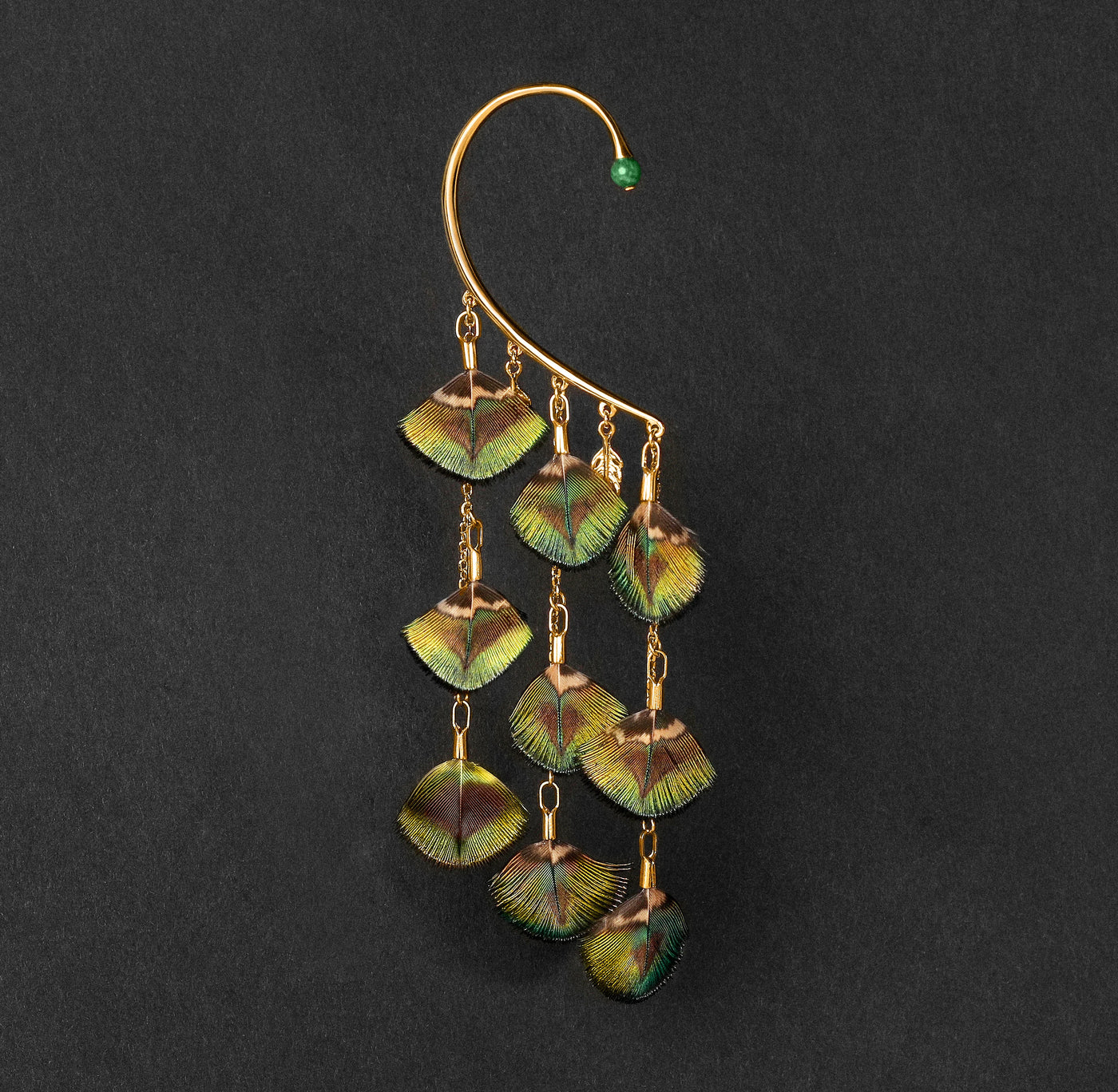 Orparima Tour d'oreille modèle "Le Paon" de la Collection Plumes, sur fond noir. Ce tour d'oreille est orné d'une Jade d'Afrique sur le devant.